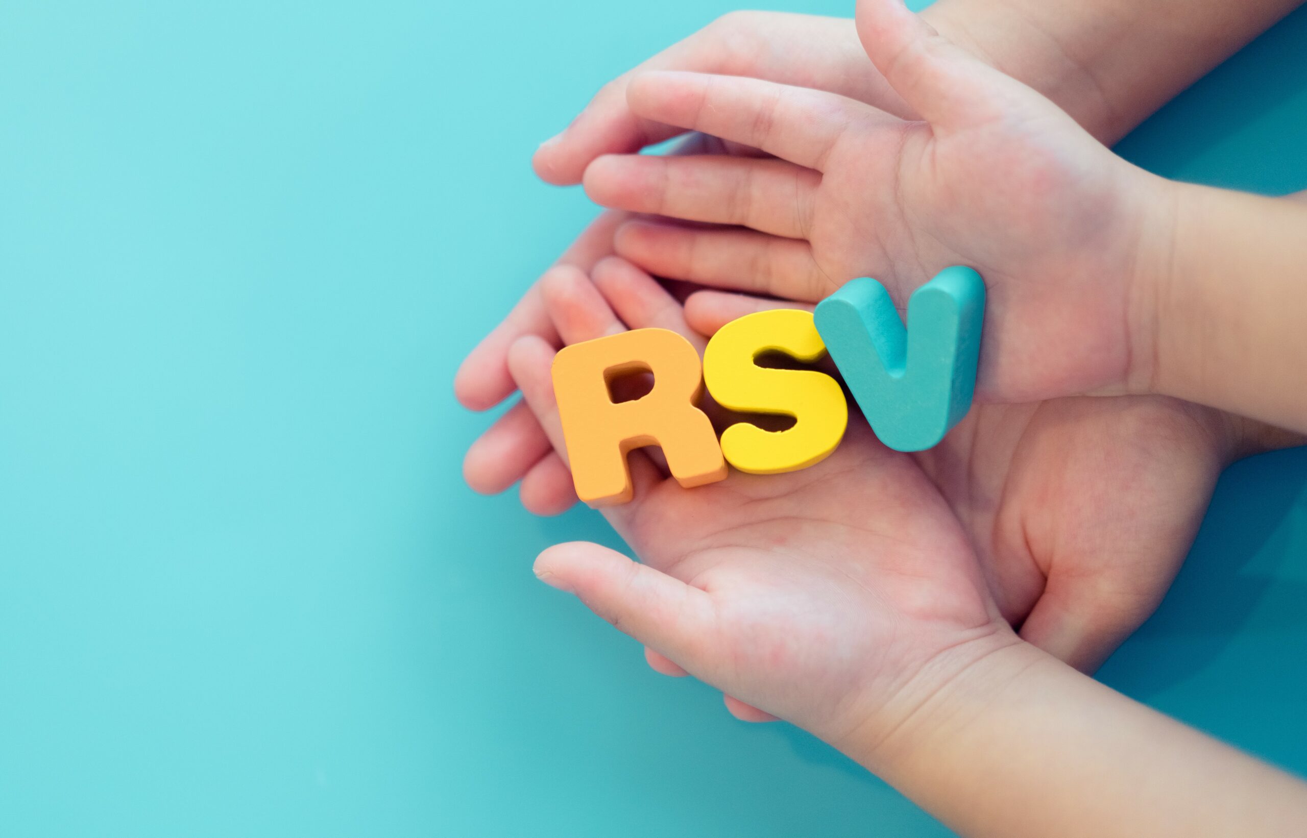 Two pairs of hands, one larger and one smaller, holding colorful letters 'R', 'S', and 'V' on a light blue background