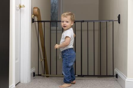 A baby standing next to a safety gate blocking the stairs
