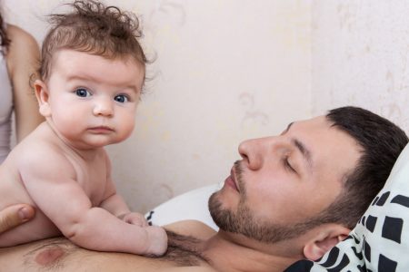 An adult having skin-to-skin contact with a baby on their chest.