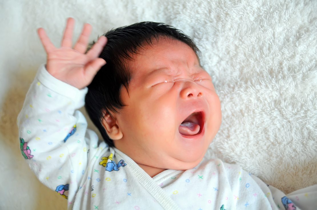 A baby crying with their mouth open.