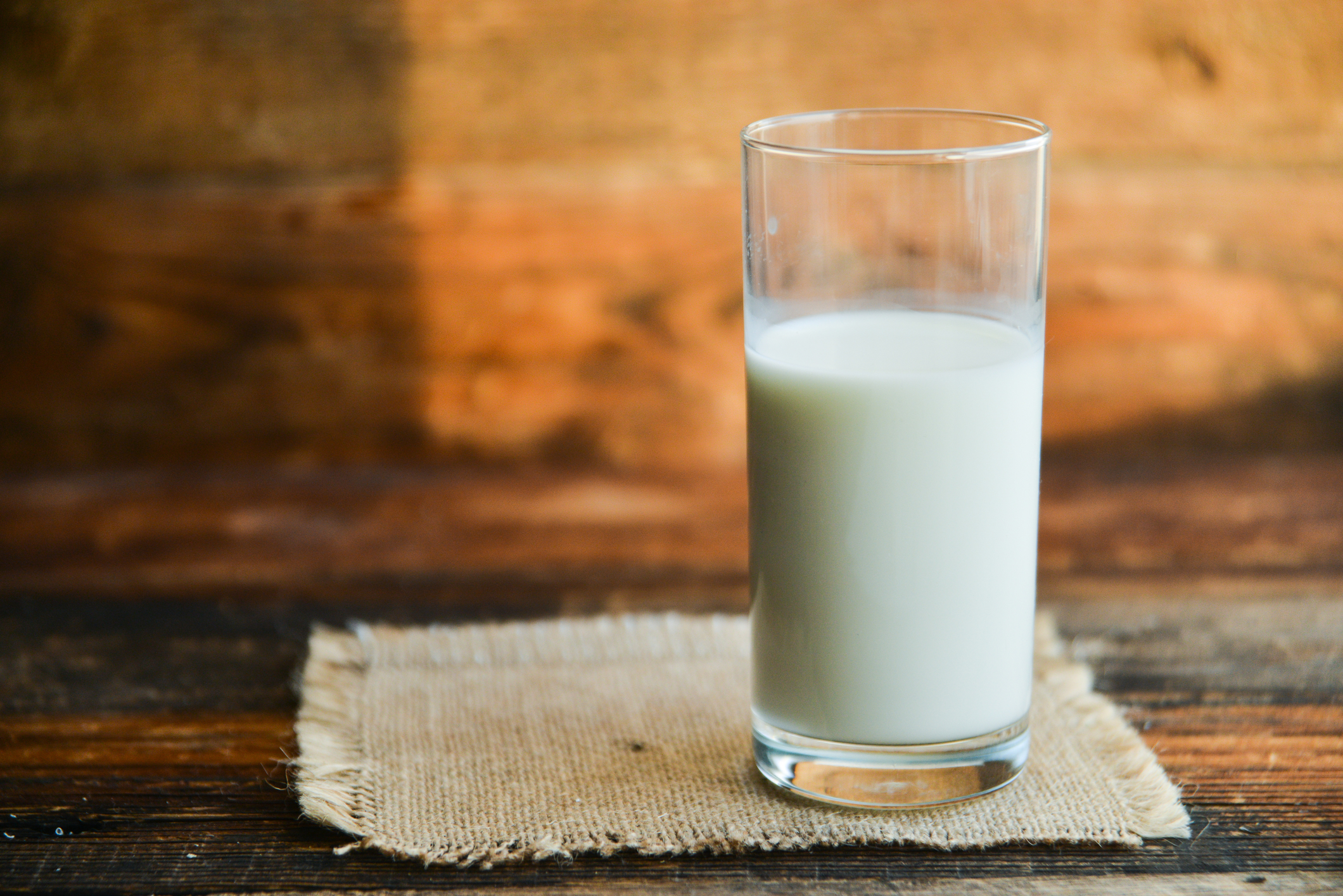 A glass of milk on a wood table.