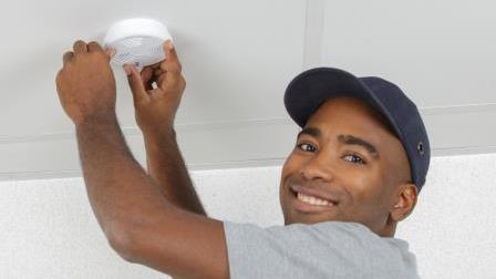 A person tests their smoke alarm.