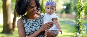 An adult holding a baby while standing outside