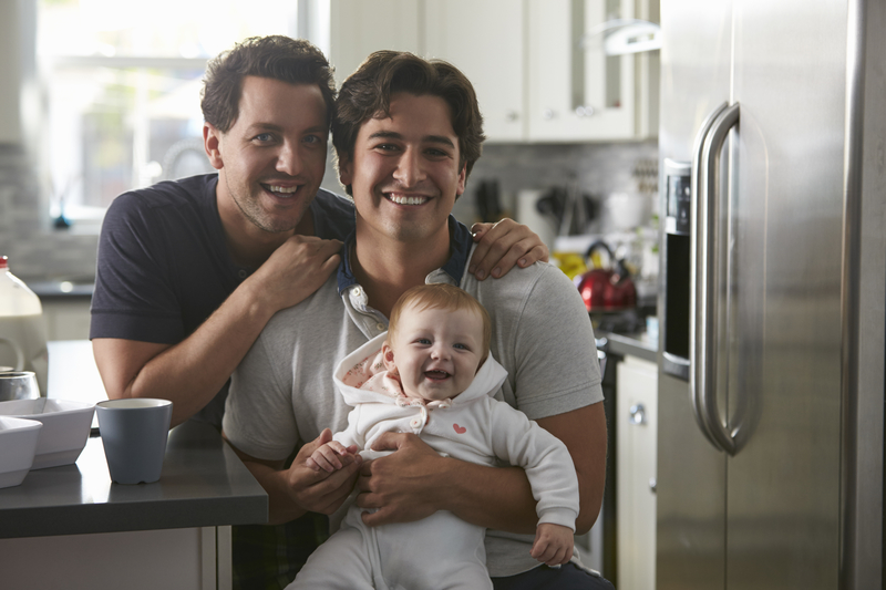 two adults smiling and holding their baby