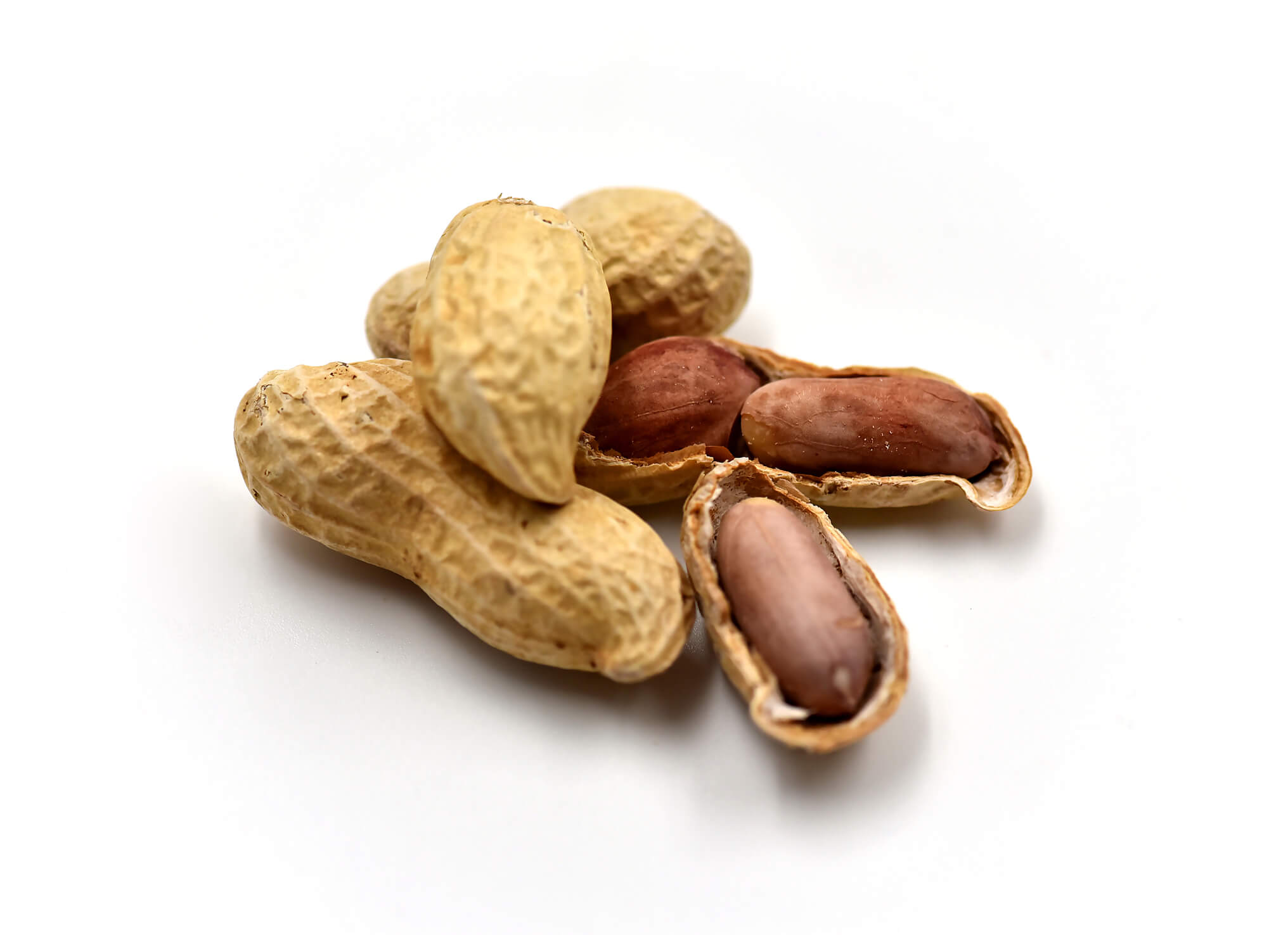 A group of peanuts, some in their shells and others partially or fully shelled, revealing the brownish-red seeds inside."