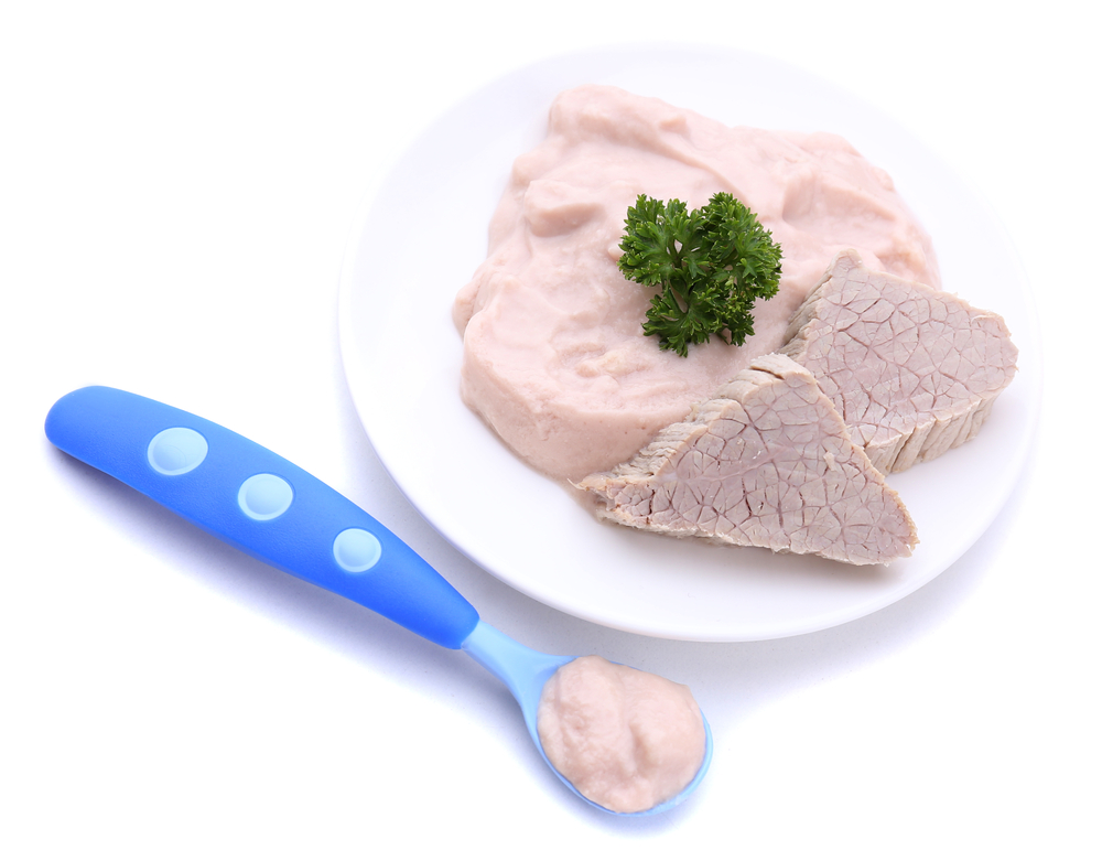 Pureed roast on a white plate with two small slices of roast and parsley on top. A blue baby spoon holding pureed meat.
