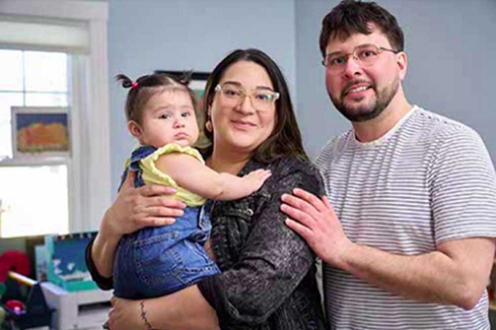 Two parents holding their baby and smiling.