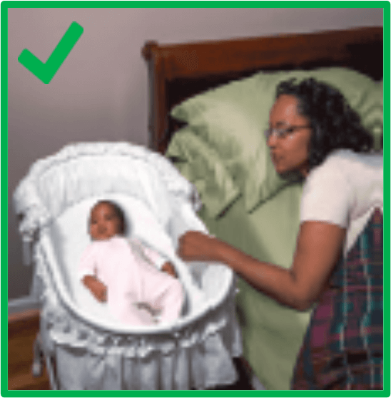 A parent looking over at their child from their bed, and touching the bassinette that the baby is sleeping in with no objects around them. There is a green border around the image and a green check mark in the top left corner.