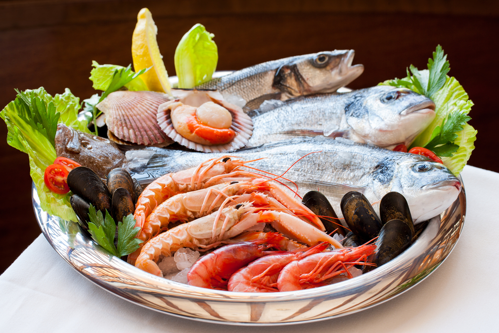 A bowl filled with seafood such as shrimp, fish, mussels, and clams.