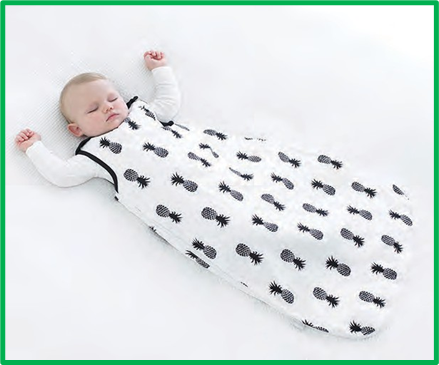 a baby in a white sleep sack with black pineapples on it, sleeping with their arms up by their ears