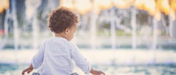 A child sitting in front of a large fountain