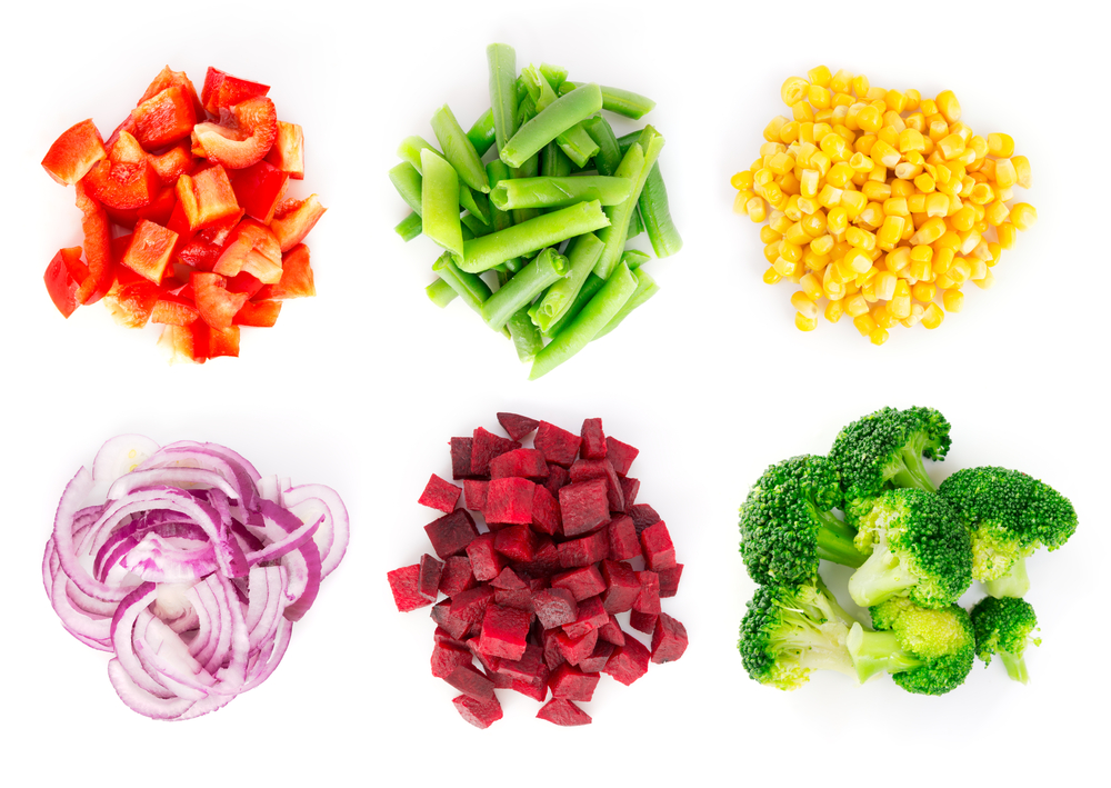 Piles of colourful vegetables including corn, red peppers, broccoli, beets, and red onion.